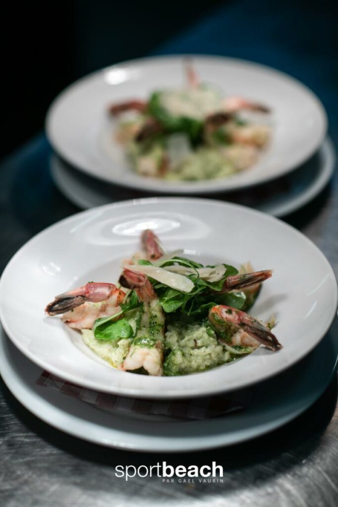 Deux assiettes blanches avec un plat à base de crevettes, feuilles vertes et une préparation crémeuse verte, présentation